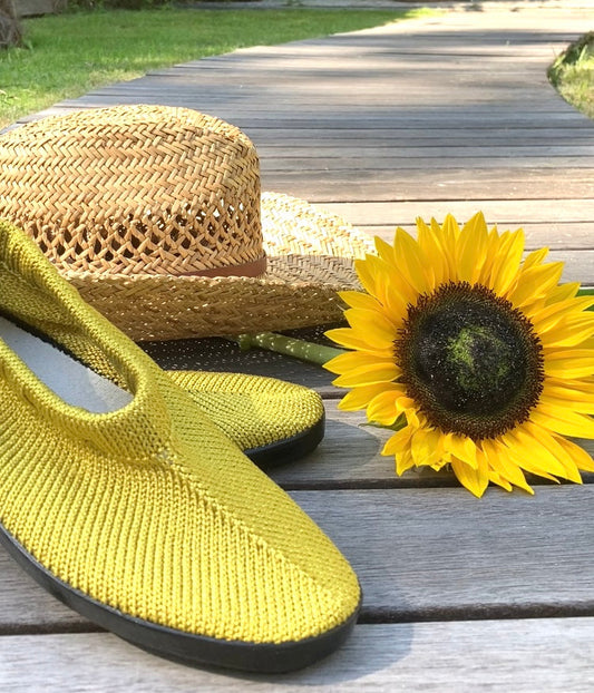 Portugese gebreide schoenen in de kleur Olive Gold, gestileerd met een strooien zomerhoed en een zonnebloem